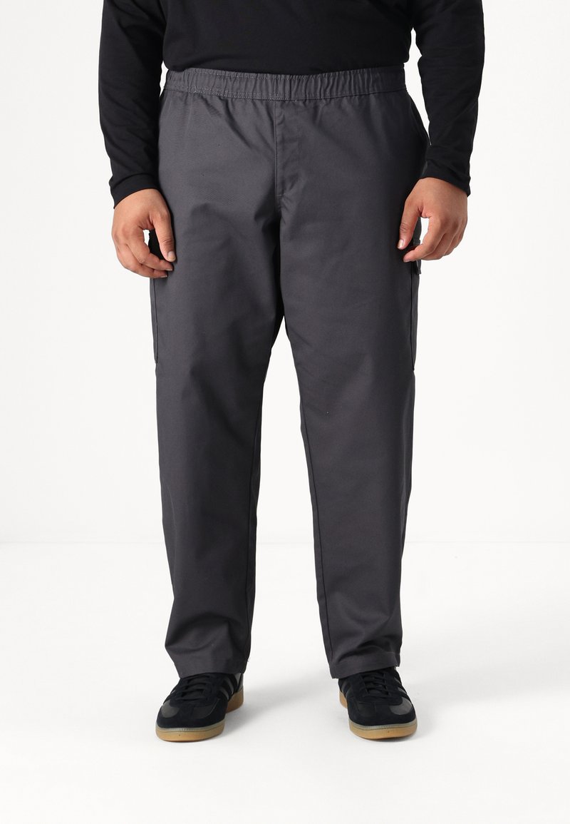 Gray, elastic-waist pants with side pockets, made of smooth fabric. Worn with black shoes featuring a gum sole and grey accents.