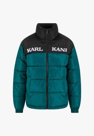 Puffer-takki, jossa musta yläosa ja turkoosi alaosa. Edessä suuri "KARL KANI" -teksti, vetoketjukiinnitys ja joustavat hihansuut.