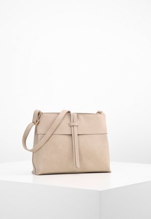 Beige leren crossbodytas met riem en voorflapdetail, gepresenteerd op een wit voetstuk tegen een effen witte achtergrond.