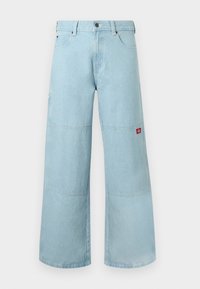 Φαρδιά τζιν σε ανοιχτό μπλε χρώμα από denim με αντιθετικές επιδιορθώσεις. Διαθέτουν κούμπωμα με κουμπιά μπροστά και μικρό λογότυπο σε μπατζάκι τσέπης στην πλευρά.