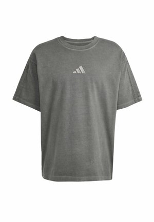 Camiseta gris de gran tamaño hecha de algodón, con mangas cortas y un escote redondeado. Tiene un pequeño logo blanco de Adidas en el pecho.