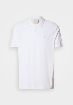 Polo blanco hecho de algodón, con cuello, mangas cortas y un pequeño logo en el área del pecho izquierdo. Diseño clásico con una textura suave.