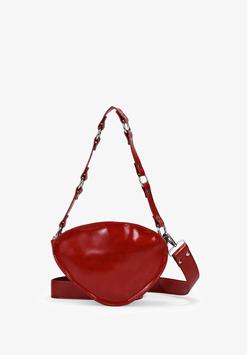 Red leather bag with a unique curved shape, featuring a chain-accented strap and a smooth, glossy texture. Adjustable strap included.
