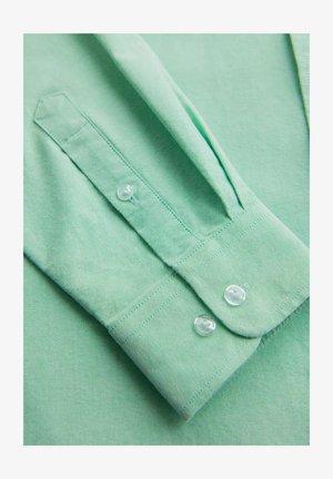 Lichtgroen overhemd met knopen en een gladde textuur, voorzien van een puntige kraag, kleine knopen en opgerolde mouwen.