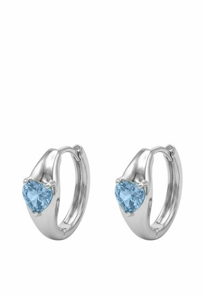 Pendientes de aro de plata, cada uno engastado con una gema azul en forma de corazón en la parte frontal, diseñados con un acabado liso y pulido.