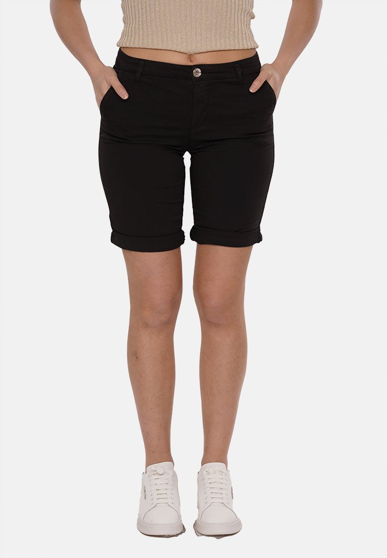 Shorts in denim nero con un design aderente, risvolti e tasche frontali. Indossati con un top lavorato e sneakers bianche.