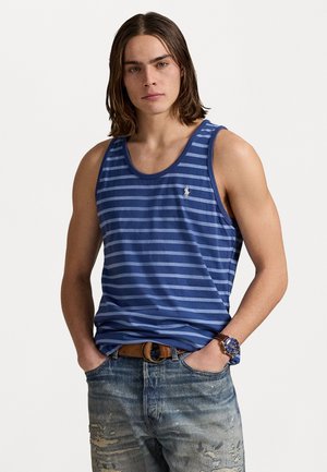 Donkerblauw en lichtblauw gestreepte tanktop van zachte stof met een ronde halslijn en een klein logo op de linkerborst, gecombineerd met versleten denim.