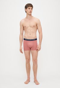 Męskie bokserki w miękkim różowym materiale o dopasowanym kroju. Posiadają granatową gumkę z logo "POLO RALPH LAUREN". Gładka faktura.