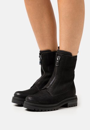 Black suede ankle boots with a rounded toe, side zippers, and textured upper. The chunky rubber sole is designed for durability and grip.