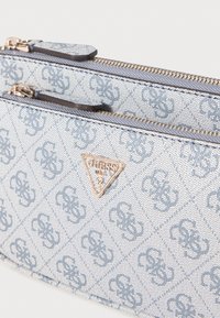 Hellblaue Clutch-Tasche im Denim-Muster mit goldfarbener Hardware, ausgestattet mit einem dreieckigen Logo und zwei reißverschlussfähigen Fächern.