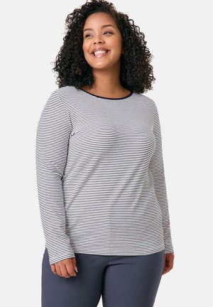 Striped long-sleeve top in white and navy with a round neckline. Soft fabric, slim fit, and fitted sleeves, paired with navy pants.