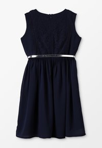 Námořnické bezrukávové šaty s krajkovou korzetovou částí, zúženým pasem a lesklým stříbrným páskem. Volná sukně sahá do poloviny lýtek; zapínání na zip na zádech.