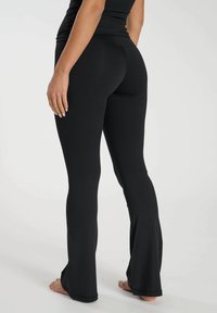 Svarta flare leggings i stretchigt material, med en slät yta och en formad midja för komfort. Minimalistisk design utan mönster.