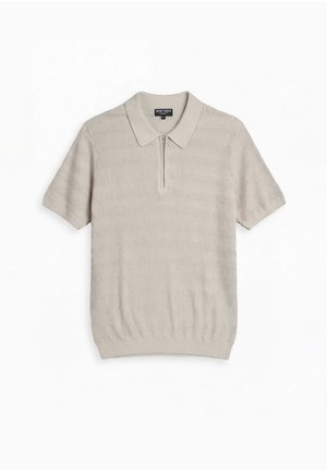 Lichtbeige, kort mouw gebreide poloshirt met rits aan de voorkant en een getextureerd golvend patroon, plat gelegd op een witte achtergrond.