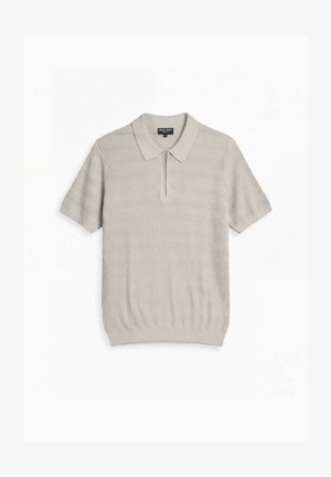 Hellbeige kurzärmliges Strick-Poloshirt mit Reißverschluss vorne und strukturiertem wellenförmigem Muster, flach auf weißem Hintergrund liegend.
