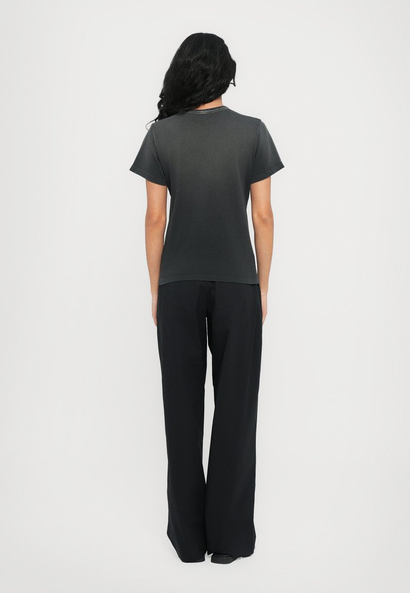 Dunkelgraues T-Shirt mit kurzen Ärmeln, aus Baumwollmaterial, lockere Passform, kombiniert mit schwarzen, weit geschnittenen Hosen, glatte Textur, minimalistisches Design.
