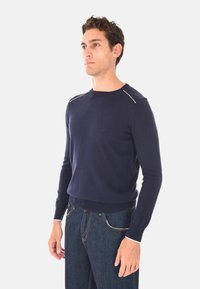 Maglione lavorato a maglia di colore blu navy, realizzato in materiale morbido, con scollatura rotonda e cuciture bianche decorative sulle spalle, dal taglio aderente.