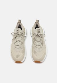 Light grey athletic shoes with a textured mesh upper, lace-up design, and white midsole. Features perforated panels and a rubber sole.