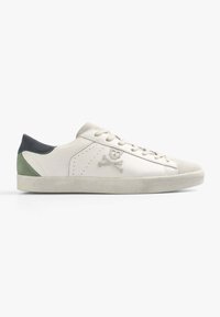 Sneaker in pelle bianca con accenti in suede grigi e verdi, caratterizzato da dettagli forati e un logo di teschio e tibie sul lato.