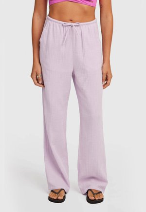 Svetlofialové široké nohavice z textúrovaného materiálu s elastickým pásom a sťahovacou šnúrkou, doplnené čiernymi šľapkami.