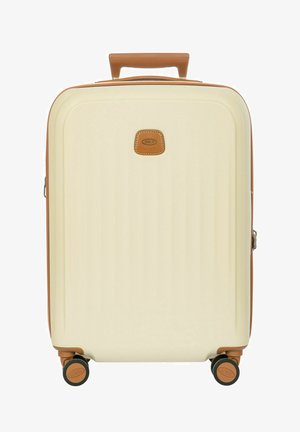 Valise rigide crème avec des accents en cuir marron, quatre roues noires et marron, et une poignée supérieure.