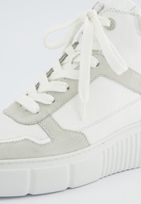 B baskets montantes en cuir blanc avec des accents en suède gris, des lacets texturés et une semelle en caoutchouc blanc nervurée. Présente un détail de logo sur le côté.