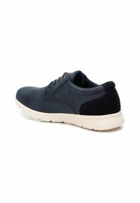 Zapatilla azul marino con un acabado de ante y suave, que presenta un diseño de cordones, cuello acolchado y una suela de goma texturizada en color blanco.