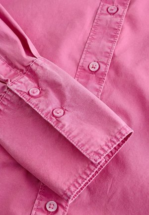 Rosa Langarmhemd mit geknöpftem Manschette, das eine glatte Textur aufweist und passende hellrosa Knöpfe entlang der Vorderblende hat.