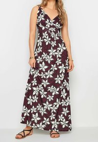 Maxi dress in deep burgundy with a floral pattern of white lilies. Features a v-neckline and adjustable straps, made from lightweight fabric.