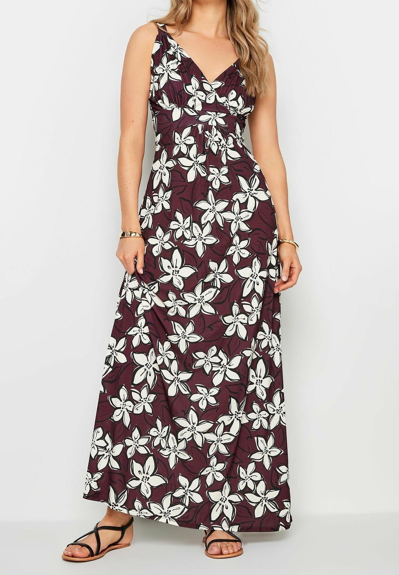 Maxi dress in deep burgundy with a floral pattern of white lilies. Features a v-neckline and adjustable straps, made from lightweight fabric.