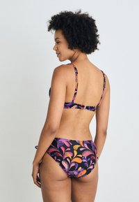 Μπικίνι σε μαύρο χρώμα με πολύχρωμο μοτίβο φύλλων. Διαθέτει ρυθμιζόμενους ιμάντες, χρυσά αξεσουάρ και σλιπ με μεσαία κάλυψη και πλαϊνές κορδόνες.