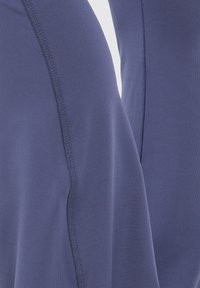 Marineblaues Sportgewebe mit glatter Textur und kontrastierenden Nähten. Nahaufnahme zeigt die Nähdetails an den Kanten.