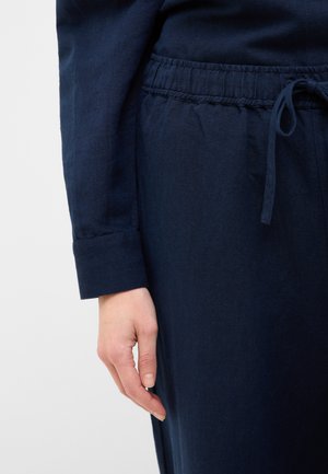 Navy blue linen long sleeve shirt with a buttoned cuff and an elastic waistband. Features a tied drawstring for adjustable fit.