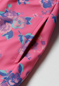 Țesătură roz cu model floral, având flori mari de culoare violet și albastru, cu o textură netedă și detalii de tiv cusute.