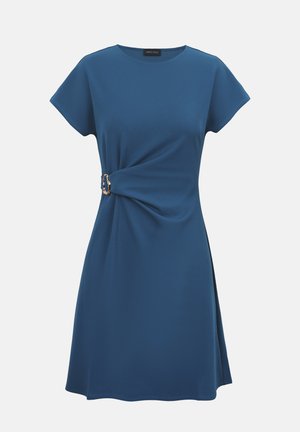 Vestido azul de manga corta con escote redondo, con un nudo lateral recogido con una hebilla dorada decorativa sobre un fondo liso.