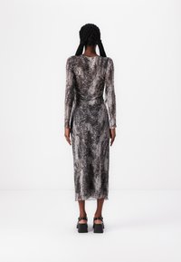 Vestido de mangas compridas em tecido texturizado com padrão de serpente preto e cinza, corpete ajustado, comprimento até à meio da panturrilha, com um detalhe de drapeado subtil nas costas.