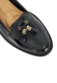 Black loafers with a textured reptile pattern, shiny patent leather accents, gold hardware, and tassels. Cushioned insole for comfort.