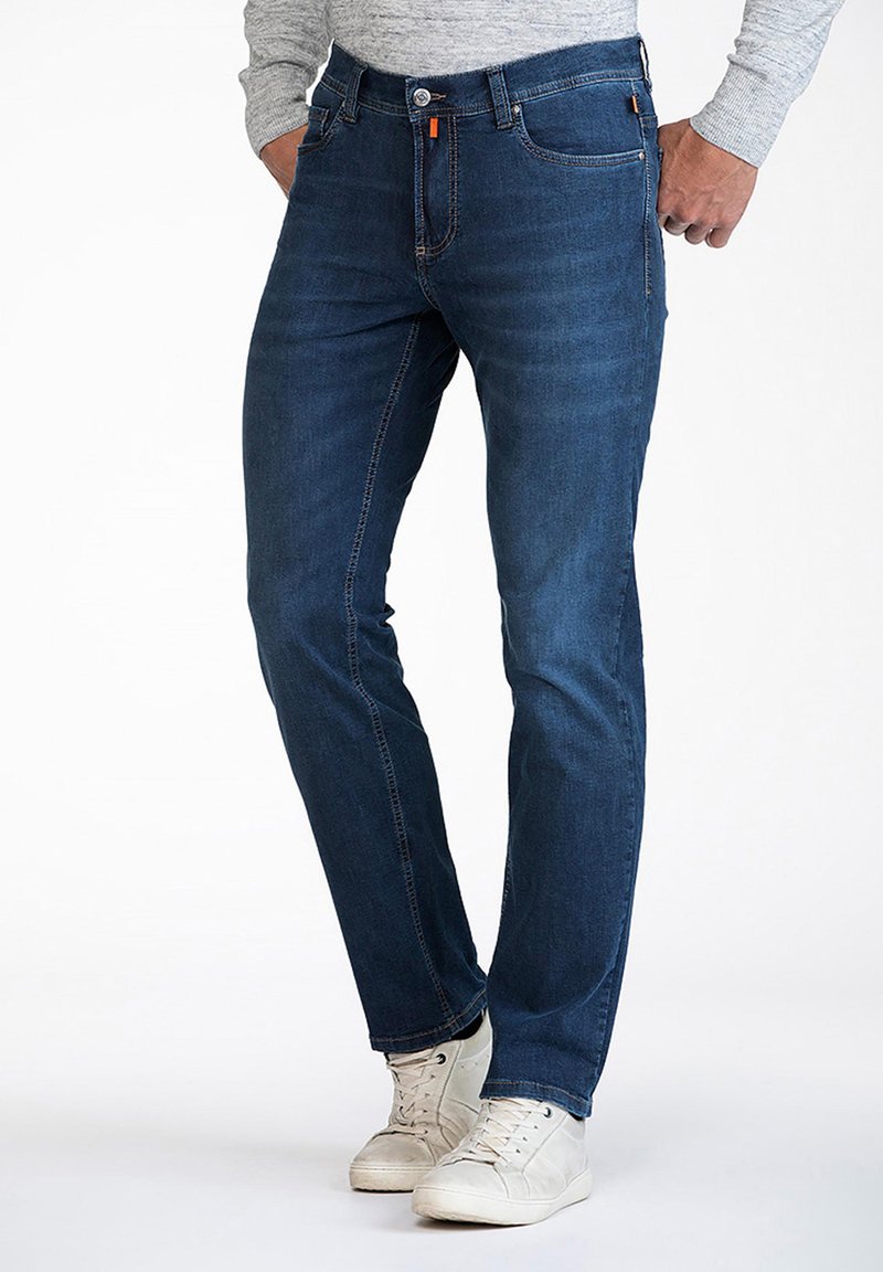 Dark blue denim jeans featuring a slim fit, front pockets, and orange stitching accents, paired with white sneakers.
