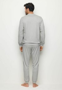 Set de trening din bumbac gri, compus dintr-o bluză cu mânecă lungă și pantaloni îngustați cu manșete ribbate. Cusături vizibile pe spate și croială lejeră.
