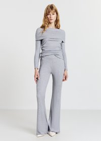 Ensemble deux pièces gris côtelé comprenant un haut à épaules dénudées et un pantalon évasé avec une finition texturée et des ourlets effilochés.