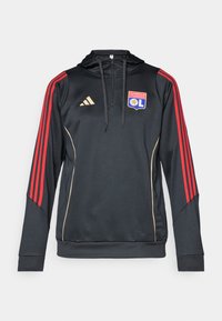 Sort hættetrøje med røde stribede ærmer, gyldne detaljer og et broderet logo af Olympique Lyonnais på brystet.