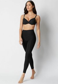 Svart sömlös bh och högmidjade leggings, båda i slät tyg. Bh:n har tunna justerbara band; leggings har en åtsittande silhuett.