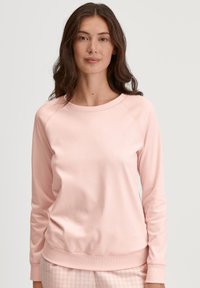 Lichtroze sweatshirt met een ronde halslijn, raglanmouwen en geribbelde rand. Zachte stof, casual pasvorm. Eenvoudig ontwerp, geen zichtbare hardware.