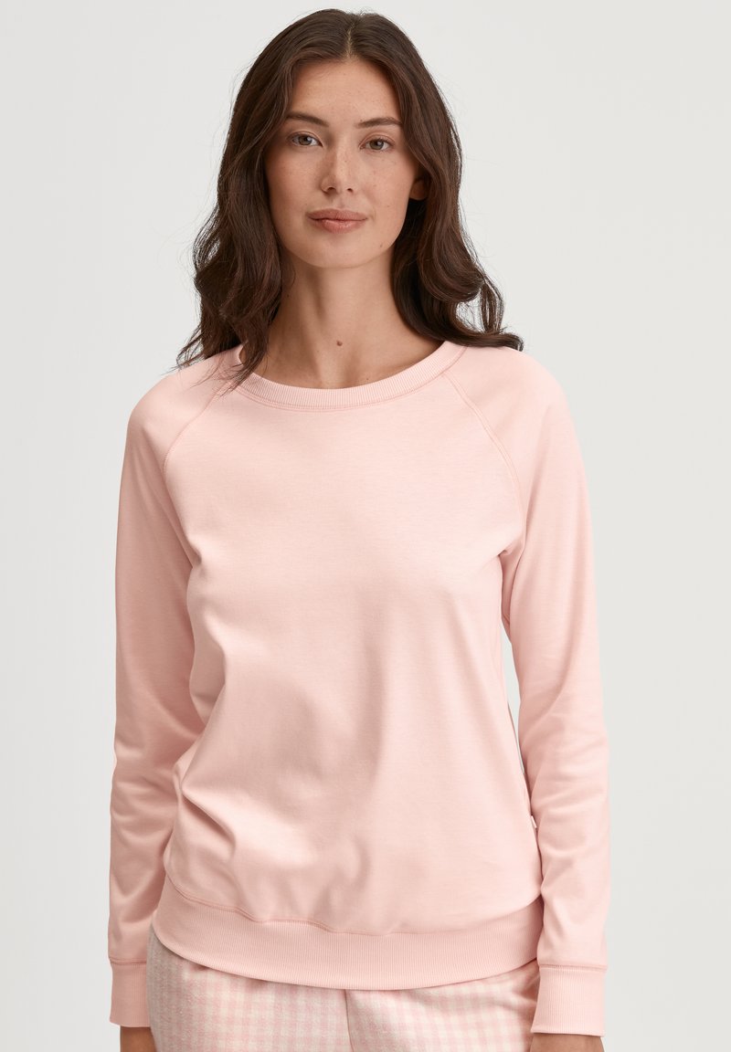 Lichtroze sweatshirt met een ronde halslijn, raglanmouwen en geribbelde rand. Zachte stof, casual pasvorm. Eenvoudig ontwerp, geen zichtbare hardware.