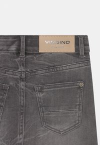 Grå denimjeans med en slät textur, med en läderlogotyp som patch, bakfickor och kontrasterande sömsdetaljer.