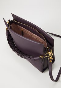 Purple leather handbag with a braided handle, gold hardware accents, and a zippered main compartment featuring an inner pocket.