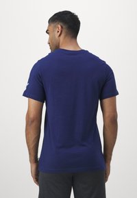 Navy blue cotton t-shirt with short sleeves and a round neckline, featuring a smooth texture and a subtle logo detail on the sleeve.