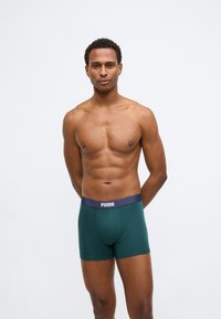 Πράσινα σλιπ μποξέρ με ναυτικό λαστιχένιο περιθώριο που φέρει το λογότυπο της Puma. Ο σχεδιασμός είναι εφαρμοστός και κατασκευασμένος από απαλό ύφασμα.