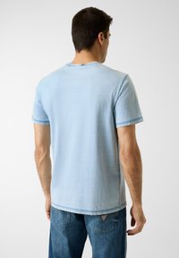 T-shirt en coton bleu clair à manches courtes, col rond classique, détails de coutures subtils, et coupe décontractée, vu de dos.