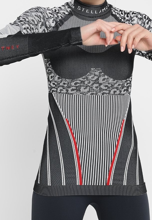 Pitkähihaista urheilu paitaa mustana ja harmaana, jossa on raidoitettu ja leopardikuosisia elementtejä. Paita on mahdollisimman istuva ja sen sivuilla on punaisia yksityiskohtia.